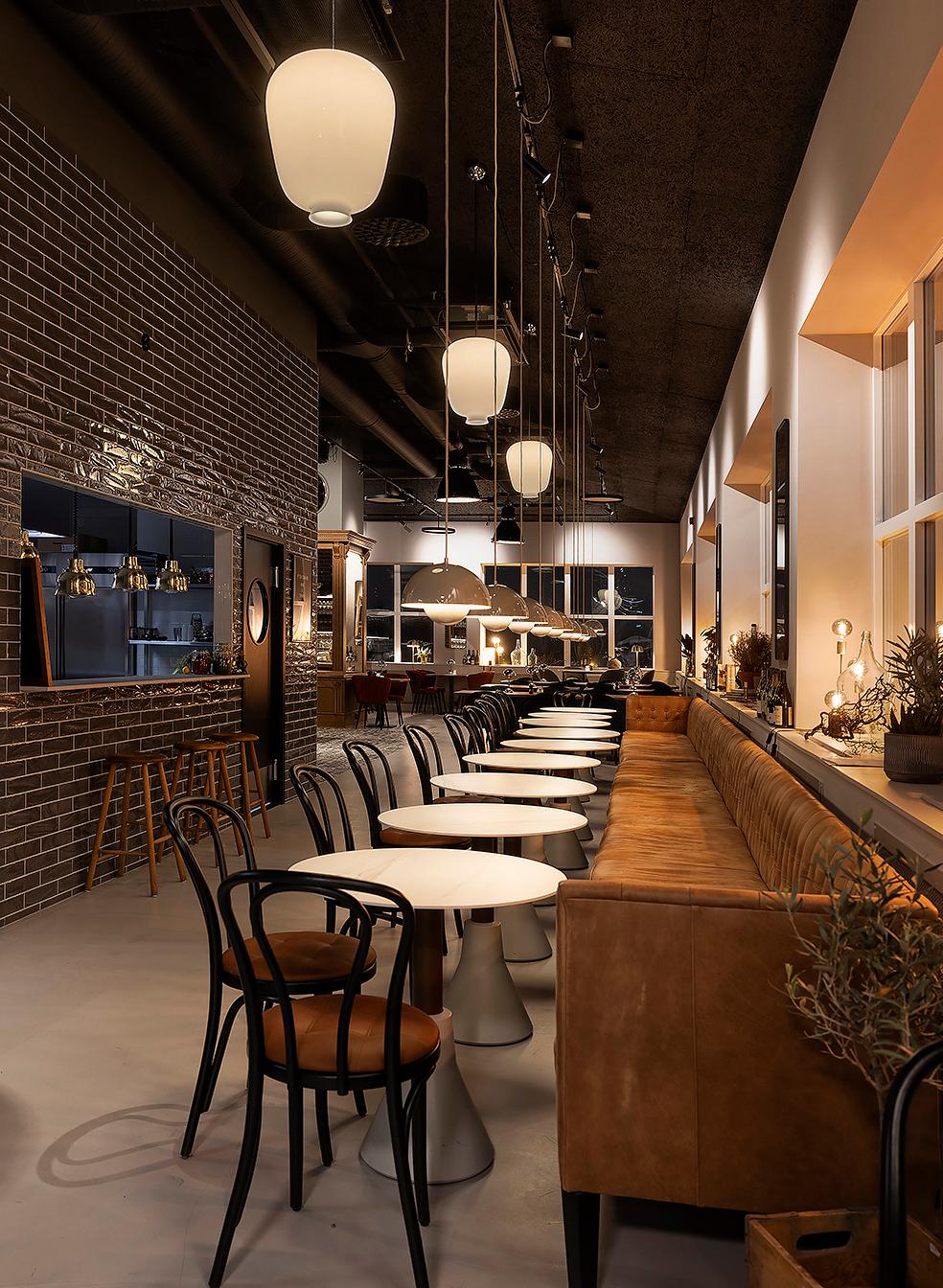 Hygges restaurang med tegelvägg, pendellampor och läderbänk